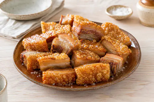 Torreznos de Soria dorados con la corteza ampollada y crujiente, servidos en un plato de barro con sal en escamas