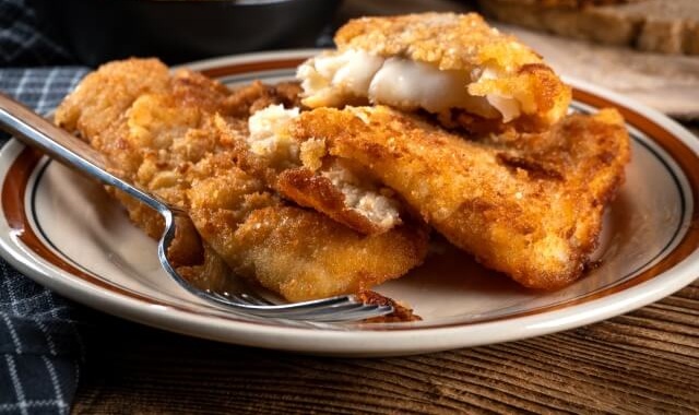 Lomos de bacalao cocinados en una freidora de aire servidos con limón y perejil.