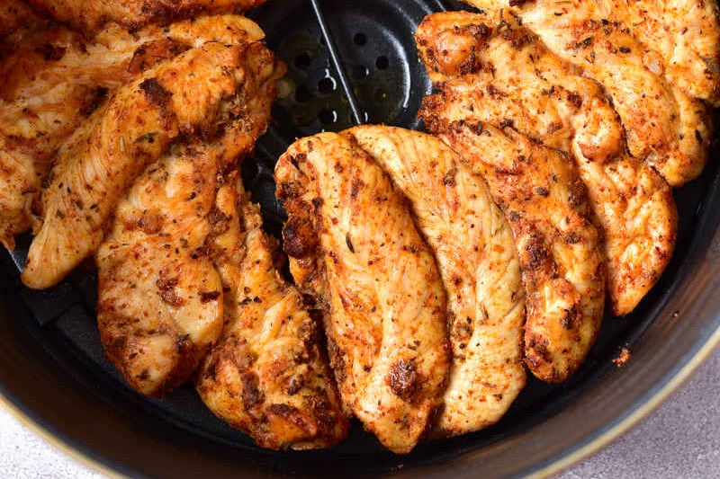Interior de pollo cocinado en freidora de aire servido con guarniciones.