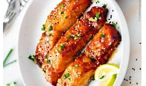 Piezas de salmón cocinadas en una freidora de aire con guarnición de verduras frescas.