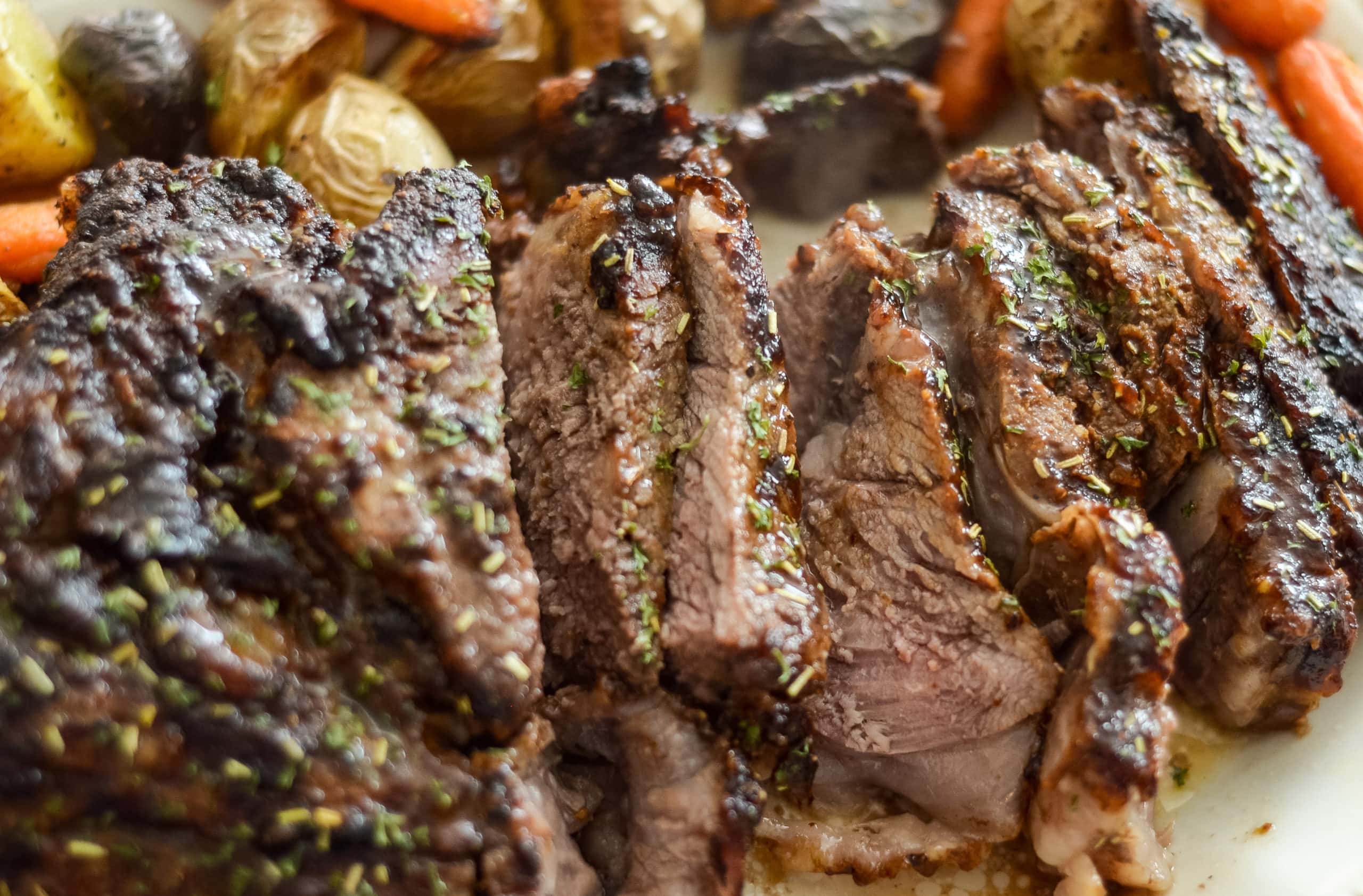 Roast beef jugoso y dorado cocinado en freidora de aire servido en un plato.