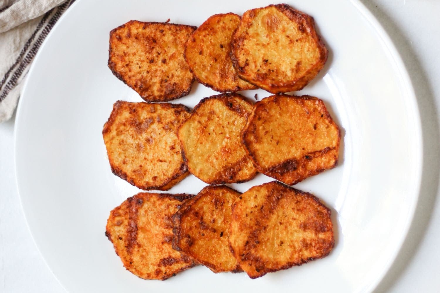 Rodajas de patata doradas y crujientes cocinadas en freidora de aire.