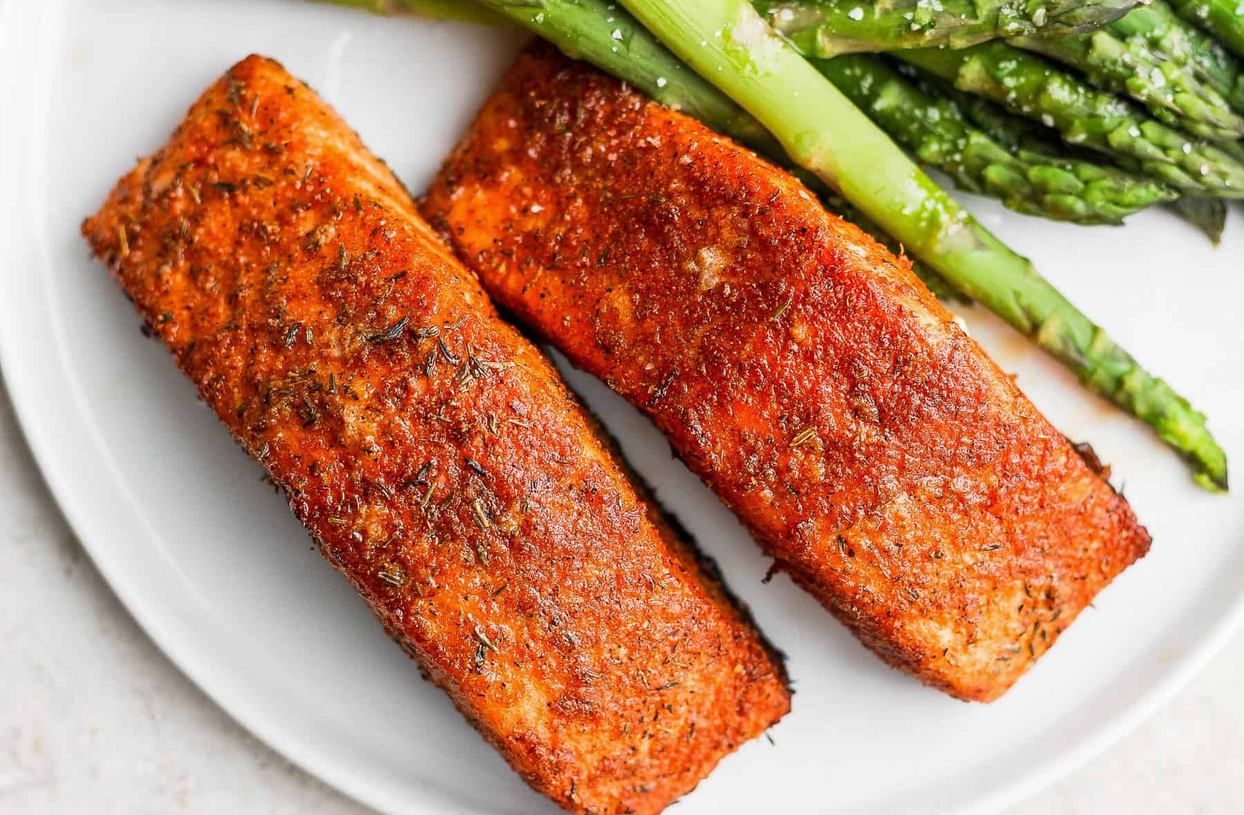 Rodajas de salmón cocinadas en una freidora de aire, servidas con limón y hierbas frescas.