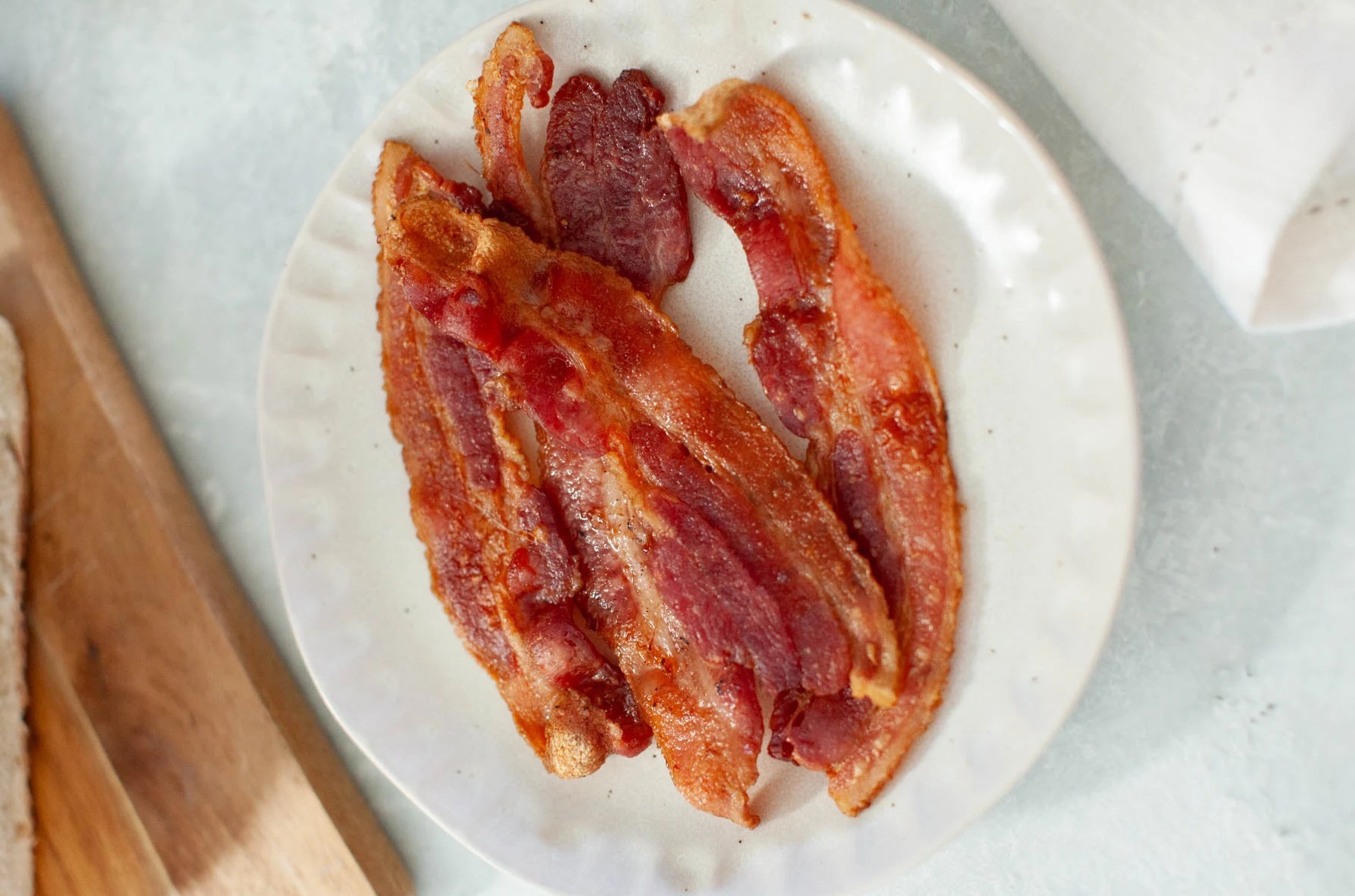 Tocino crujiente cocinado en freidora de aire servido en un plato.
